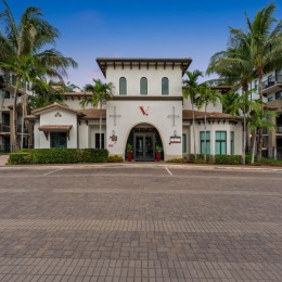 a white building with a parking lot and palm trees